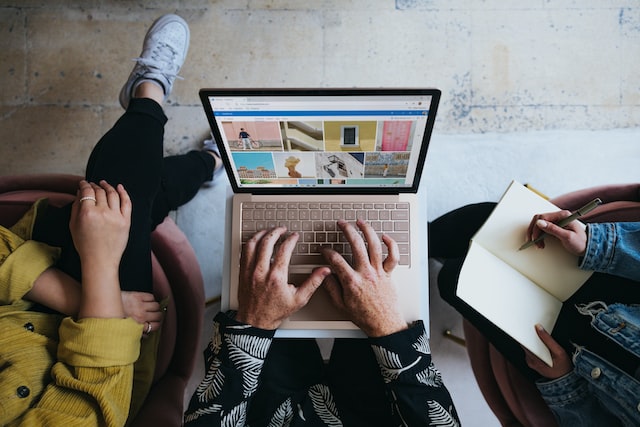 Overhead shot of three people sitting next to each other, the one in the middle is holding a laptop